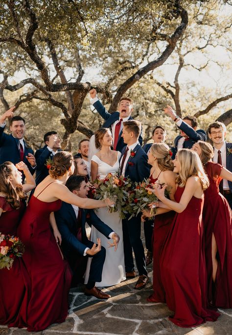 Fun excited wedding party surrounding bride and groom on wedding day wearing red bridesmaid dresses and groomsmen in blue suits Trending Bridesmaid Dresses, Deep Red Wedding, Spanish Mission, Wedding Colors Red, Red Wedding Theme, Red Rose Wedding, Blue Suit Wedding, Maroon Wedding, Bridesmaid Colors