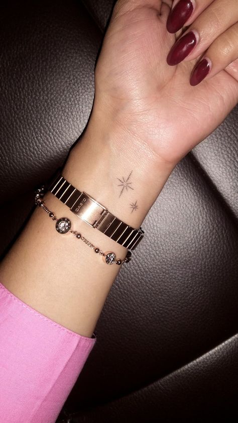 Wrist is shown with a rose gold bracelet and watch, and a tattoo of two little sparkles. Hand Tattoos Sparkles, Hand Sparkle Tattoo, Sparkles Tattoo, Tattoos On Arm, Sparkle Tattoo, Small Star Tattoos, Baby Tattoo Designs, Baby Tattoo, Arm Tats