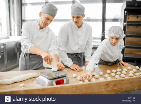 Download this stock image: Three young bakers in uniform forming dough for baking on the wooden table standing together at the modern manufacturing - MTF15X from Alamy's library of millions of high resolution stock photos, illustrations and vectors. Baker Uniform, Cake Bear, Baking Buns, Cake Bakery, Dough Balls, Unique Business Cards, Cake Baking, Bakery Cakes, Professional Business Cards