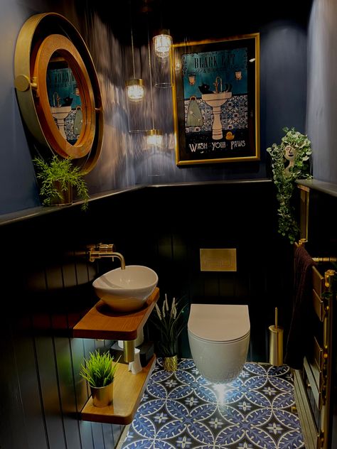 Downstairs cloakroom with wall hung toilet and sink. Victorian style floor sets off the lower tongue and groove boarding painted in F&B Railings and the upper wall and ceiling painted in F&B Stiffkey Blue. Brushed gold flush plate, taps and accessories add to the glamorous feel. Warm oak floating shelves, plants,  and a vintage style poster in a gold frame soften the look. A cascading chandelier, low power spot lights and lighting under the loo and sink shelves provide plenty of warm light Industrial Bathroom Ideas, Small Downstairs Toilet, Toilet Ideas, Bathroom Inspiration Modern, Downstairs Toilet, Industrial Bathroom, Small Bathroom Makeover, Small Bathroom Ideas On A Budget, Small Bathroom Ideas Modern