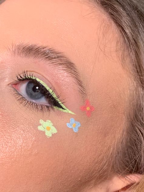 black winged eyeliner w pastel green outline, and 3 pink blue and green flowers going from cheek bone to brow Cute Flower Makeup, Makeup Primavera, Flower Art Makeup, Flowers Eye Makeup, Flower Halloween Makeup, Floral Eyeliner, Flowers Face Paint, Flower Makeup Aesthetic, Flower Power Makeup