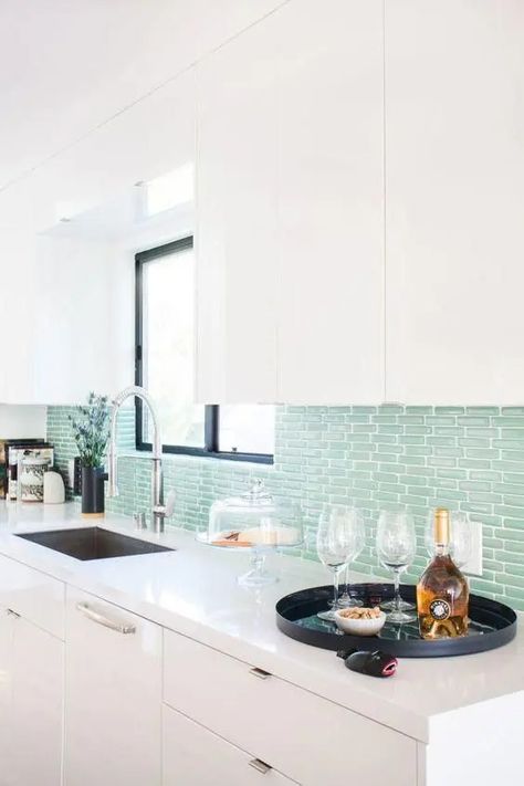 a modern white kitchen with sleek cabinetry, a mint green tile backsplash, black touches and white stone countertops Nautical Kitchen Decor, Beachy Kitchen, Mint Green Kitchen, Turquoise Kitchen Decor, Meridian House, Nautical Kitchen, Brick Backsplash Kitchen, Beach Kitchen Decor, Open Kitchen And Living Room