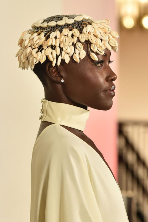 Lupita Nyong'o attended the GO Campaign Annual GO gala looking like royalty with cowrie shells Cowrie Shell Headband, Cowrie Shell Locs, Cowrie Shell Headpiece, Shell Fashion Design, Cowrie Shell Tattoo, Intricate Headpiece, African Headpiece, Shell Headpiece, Intricate Hairstyles