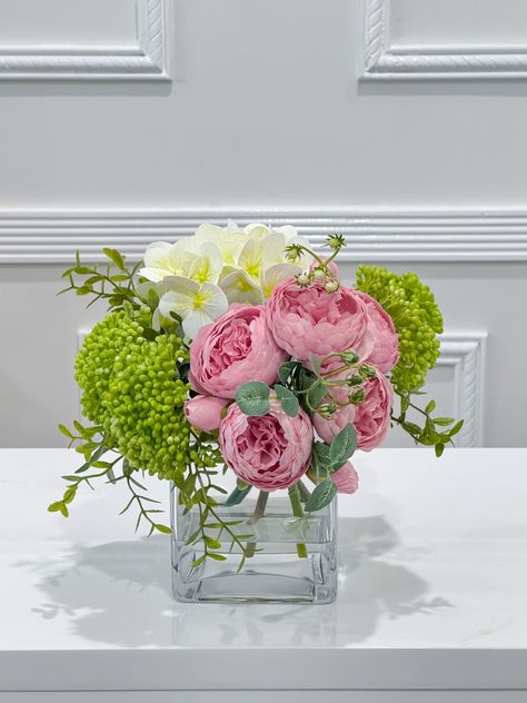 This premium lovely flower arrangement design includes  finest silk peonies, real touch hydrangea and green berries  filled with faux water in glass vase. This elegant arrangemenr can bring nature inside and brighten your space, especially for small tables at home, vanity tray, book shelf, small night stand, end table or office desk. FLOVERY™ takes pride in designing realistic and high-quality artificial flowers. Each flower is made with our real touch technology, giving them a natural look and Hydrangeas And Roses Centerpiece, Centre Table Flower Arrangement, Peony Arrangement Ideas, Square Vase Flower Arrangements, Real Flower Arrangements, Faux Hydrangea Arrangement, Small Night Stand, Small Vases With Flowers, Peony Flower Arrangements