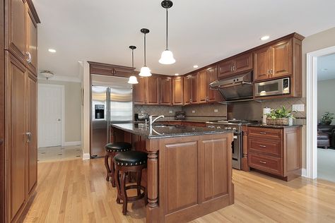 Large island with decorative pillars highlights the darker wood contrasting with a light toned floor in this open designed kitchen. Cypress Cabinets, Brown Kitchen Cabinets, Dark Wood Kitchens, Cherry Kitchen, Brown Cabinets, Cherry Cabinets, Brown Kitchens, Popular Kitchens, Wood Kitchen Cabinets