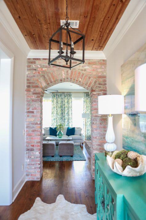 Hallway. Brick wall with arched door. Warm wood ceiling with white trim. Turquoise painted hall table. Lantern pendant. Brick Fireplace Arch, Brick Wall Wood Ceiling, Exposed Brick Entryway, Brick Wall Foyer, Arched Brick Entryway, Brick Foyer Entryway, Brick Entryway Wall, Brick Doorway, Stile Joanna Gaines