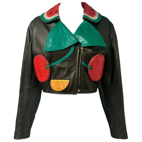 Whimsical rare vintage Moschino black cropped moto leather jacket with colorful fruit appliques. This unique jacket features a watermelon collar, cherry zip pockets, oranges, cherry cuffs, and bananas. Embroidered with "SIAMO ALLA FRUTTA!" on the back. Size: There is no size tag present, please refer to measurements for the best fit. Condition: In excellent condition with light wear throughout. Measurements: Bust- 34" Waist- 30" Length- 20" Note that this piece has lived a previous life, and its story may be reflected in minor imperfections. Atom Punk Fashion, Funky Leather Jackets, Vintage Cropped Leather Jacket, Moschino 90s, Wacky Fashion, Fun Jackets, Funky Jacket, Retro Futurism Fashion, Moschino Vintage 1990s