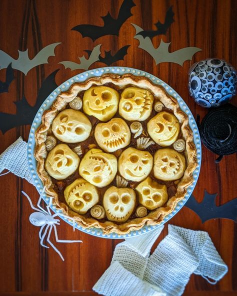 A round apple pie with faces carved into apples on the top. Halloween Apple Pie Ideas, Spooky Apple Pie, Skull Apple Pies, Apple Pie Halloween, Spooky Snack Ideas, Halloween Pie Crust Designs, Halloween Apple Desserts, Creepy Baking, Spooky Bakery