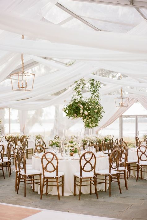 Looking for a way to create a luxurious look while maintaining a simple, elegant look? Layers are the way! Creating layers with drape and our elegant Darby Chandelier fills the negative space with a romantic design that enhances the romantic ambiance. Visit our website to view past event transformations! #WhiteWedding #ElegantWedding #GoldChandelier #WeddingGreenery #CharlestonSC #Tent #Layers #Drape #Florals #WeddingReception #EventLights Simple Wedding Reception, Wedding Planning Organizer, Warm Color Schemes, Boat Wedding, Simple Wedding Decorations, Wedding Planning On A Budget, Elegant Wedding Reception, Outdoor Wedding Inspiration, Wedding Planning Guide