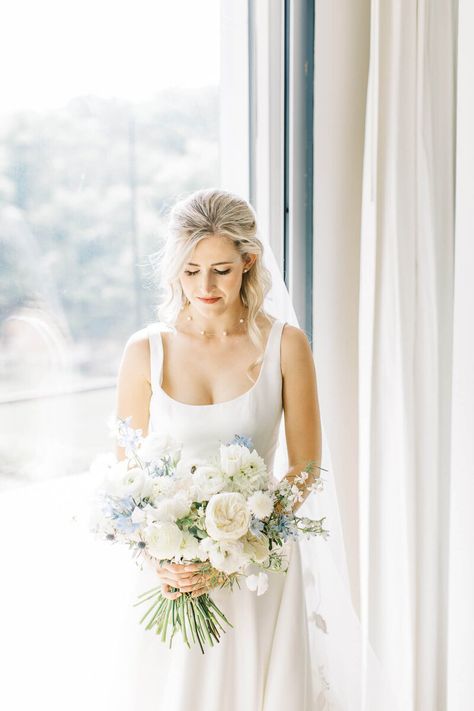 White and light blue garden style wedding bouquet for summer weddings with white Garden roses, white Tulips, white Scabiosa, light blue Delphiniums, whitet Ranunculus, white Basket flowers, and light blue Tweedias. White Garden Style Bridal Bouquet, White And Light Blue Bridal Bouquet, White Flowers With Blue Accents, Light Blue Garden Wedding, Coastal Bridal Bouquet, White Bouquet With Blue Accents, Light And Airy Wedding Photos, Light Blue And White Bouquet, Blue And White Bridesmaid Bouquet