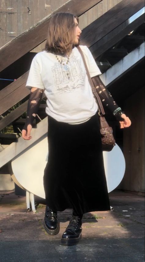 A mid-size person/girl wearing a black thrifted ripped stockings longsleeve, a white wide graphic shirt over it, a wide dark black velvet maxi skirt, black platform dr. Martens and multiple crystal rings and bracelets. 	The person is also wearing multiple silver necklaces, one in form of a moon and another in form of a fairy  necklace, a brown rosary-style fairy bead necklace, a vintage necklace and a black lace choker. Platform Grunge Outfit, Skirt Outfits With Dr Martens, Basic Long Skirt Outfit, Ripped Tights Shirt, Long Skirt Band Tee Outfits, Velvet Maxi Skirt 90s, Long Black Skirt Grunge Outfit, Grunge Outfits Maxi Skirt, Choker Outfit Grunge