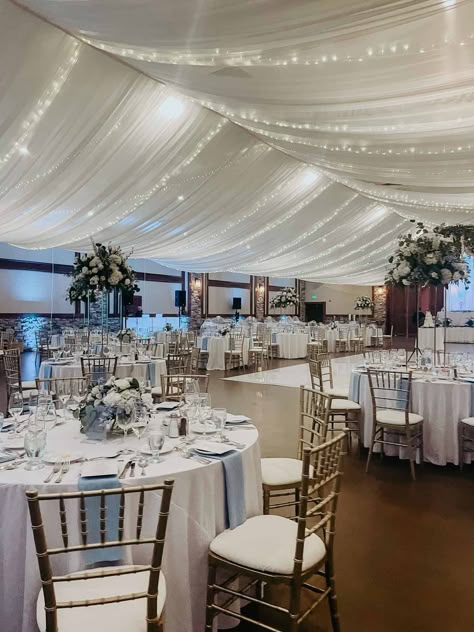 Add an extra touch of elegance to your wedding reception with sheer ceiling draping and twinkle lights. The fabric creates a soft, romantic ambiance in any space, while the twinkle lights add a whimsical touch. #illumepghdesign #pittsburgheventdesign #pittsburghevents #eventdesign #weddingdesign #eventdecorator #weddingdecorator ⁠#events #eventprofs #realwedding #pittsburghwedding #weddinginspiration #weddingdetails #ceilingdraping #twinklelights Wedding Hall Draping Ceiling Decor, White Draped Walls Wedding, Hall Draping Wedding, Hanging Tulle From Ceiling, Reception Draping Ideas, Ballroom Ceiling Decorations, Wedding Ceiling Draping With Lights, Tulle Draping Wedding Ceiling Decor, Party Drapery Ideas