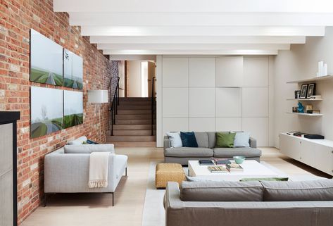 The sofas in this room, which is mainly used by the teenage children in the family, are from [link url="https://www.flexform.it/en"]Flexform[/link] and [link url="https://www.bebitalia.com/en"]B&B Italia[/link], with a standard lamp from [link url="https://flos.com/"]Flos[/link]. Martin designed the wall of cupboards on the back wall, while another wall is clad in reclaimed bricks. A set of graphic landscapes by contemporary artist Julian Opie hang in the basement sitting room. His work is avail Wall Of Cupboards, Mdf Shelving, Julian Opie, Built In Wardrobes, Storage Closets, Standard Lamp, Side Extension, House In London, Stone Interior