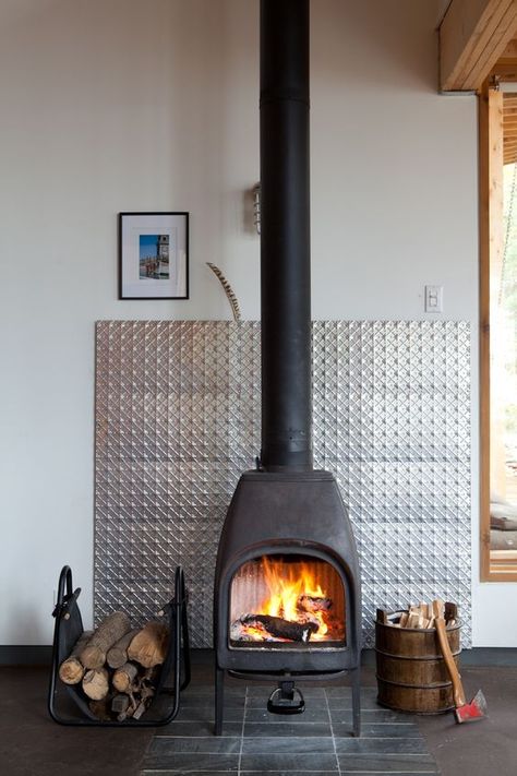 A metal panel protects the wall behind a wood-burning stove and adds a visual focal point within a Canadian vacation home. Photo by: Lorne Bridgman Wood Stove Surround, Modern Wood Burning Stoves, Wood Stove Fireplace, Freestanding Fireplace, Into The Wood, Stove Fireplace, Post And Beam, Wood Burner, Metal Panels