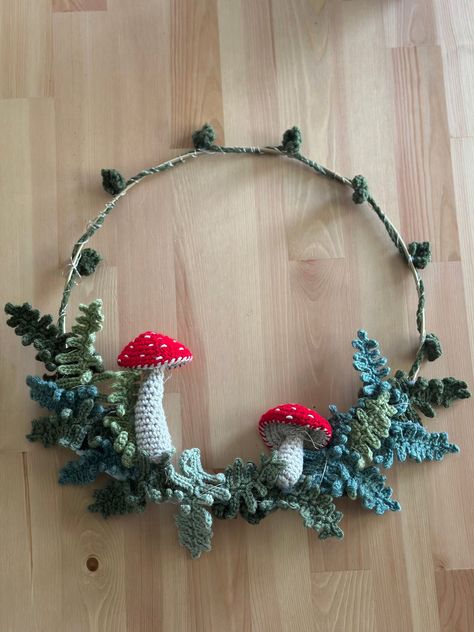 12 inch metal wreath, with hand crochet fern leaves, vine, and magic mushrooms. Option available to add fairy lights, in rainbow, or white for additional $6