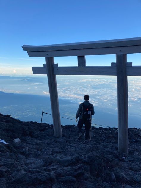 Man walks through a wooden Japanese Torii gate, an archway of wood. Beyond you can see an impressive view of mountains and sea from the top of Mount Fuji. Climb Mt Fuji, Climbing Mount Fuji, Mount Fuji Hike, Mountains Japan, Japan Hiking, Japan Mountains, Mt Fuji Japan, Japan Beach, Japan Tourist