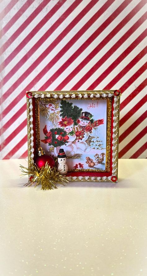 Make your holiday merry with this handcrafted retro shadow box diorama featuring a scene from a vintage Christmas card. The painted box is decorated with sparkly chenille stems, ribbon, an ornament, garland, and a painted wood snowman. Can be hung on the wall or set on a shelf. Crafted with love for all things vintage, festive, and sparkly! Vintage Christmas Shadow Boxes, Vintage Christmas Shadow Boxes Dioramas, Vintage Christmas Wall Decor, Christmas Vignettes Display, Diy Christmas Shadow Box, Shadow Box Crafts, Christmas Frames Diy, Picture Frames Diy, Christmas Assemblage