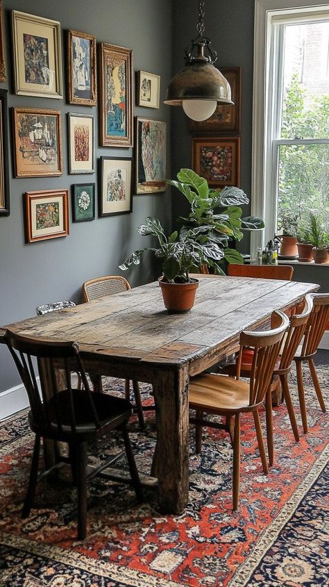 Eclectic dining room with rustic wooden table, mix of chairs, vibrant Persian rug, potted plants, framed artwork, and natural light from a large window Eclectic Dining Room, Eclectic Dining, Rustic Wooden Table, Large Window, Eclectic Design, Rustic Table, Wooden Table, Dining Room Design, Large Windows