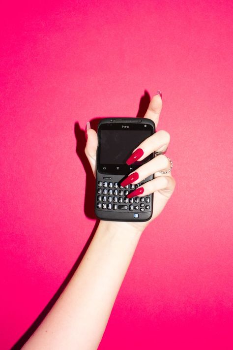 Hand with long nails holding an old phone, pink aesthetic. Red nails, pink background, Htc phone, blackberry old mobile, flashlight, direct flash, bitchy, long fake nails. #photography #flashphotography #pink #brightpink #phone #hand #flash #nails #rednails #fakenails #stock #oldphone #phone Phone Pink Aesthetic, Aesthetic Red Nails, Flash Nails, Htc Phone, Long Fake Nails, Hand Holding Phone, Nails Photography, Holding Phone, Food Nails