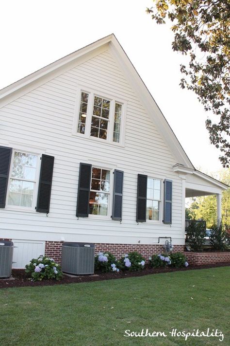 brick foundation on southern living idea house Exterior Foundation Ideas, White House Brick Foundation, Brick Underpinning White House, White Vinyl Siding House With Brick, White House With Red Brick Skirting, Brick Skirting House Exterior, Brick Foundation Exterior, White Farmhouse Brick Foundation, White Brick House With Shutters