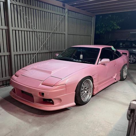 Pink 180sx JDM car with rhinestone side mirrors parked under fluorescent lighting in a garage with a brown vertical slat fence. Owner is Fivedimes.co Pink Jdm, 180sx Nissan, Formula 1 Cars, Nissan 180sx, Car Photoshoot, Cars Aesthetic, F1 Car, Aesthetic Car, Mom Car