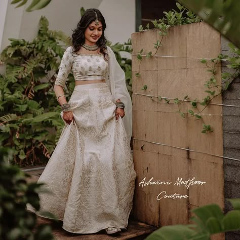 Ashwini Mathoor on Instagram: "An exquisite lehenga in a snowbound color, completed with a lustrous silk blouse with beautiful hand - embroidery and a flattering silhouette. The timelessness of Beauty❤ D Gorgeous Bride Meenu swoon under the spell of an off-white banarasi lehenga paired with blouse handembroidered using zari and sequins. The lehenga is a wonder.😍 The bridal edit is exquisitely constructed using the finest fabrics and the most detailed finishings. #signaturelehenga #AshwiniMa Bridal Lehenga Kerala, Off White Banarasi Lehenga, Wedding Skirt And Top Indian, Save The Date Dress Kerala, Lehenga For Onam, Maduramveppu Dress Kerala, Banarasi Bride, Kerala Lehenga, Hindu Engagement Dress Kerala