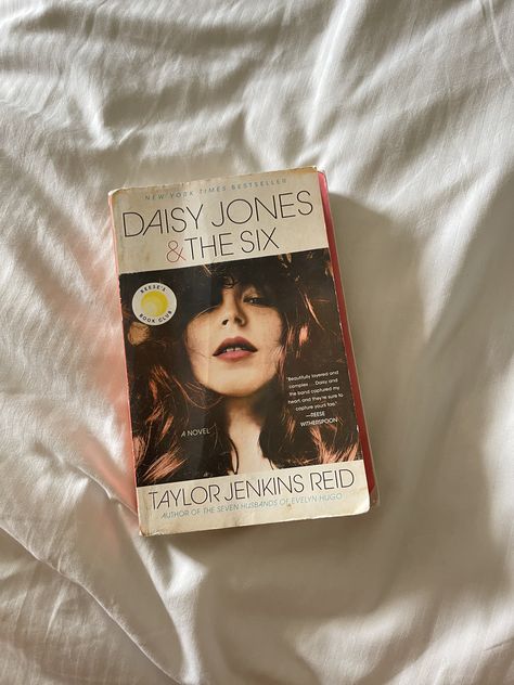 A well-loved paperback copy of the book Daisy Jones & The Six by Taylor Jenkins Reid lays atop a bedsheet. Daisy Jones And The Six, Fall Reading, Daisy Jones, Unread Books, 2023 Vision, Beach Reading, Any Book, Instagram Story Ideas, Winter Theme