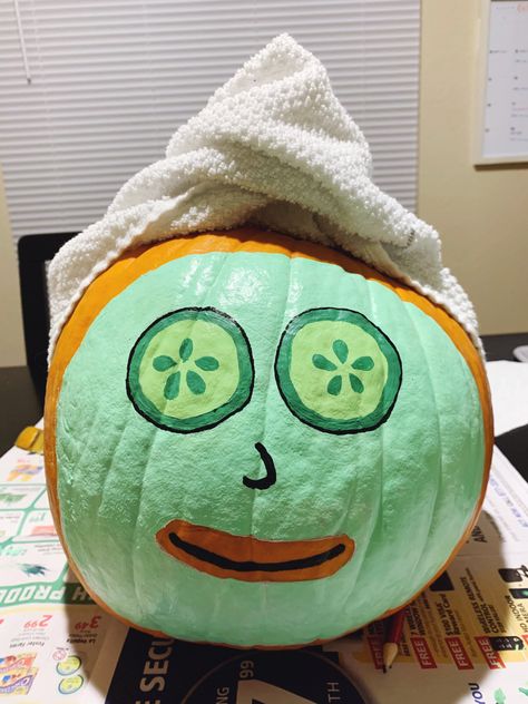 Medium sized pumpkin with green face mask and cucumber eyes, topped with a wrapped towel covering the stem. Pumpkin Painting Ideas￼, Yellow Painted Pumpkin Ideas, Halloween Pumpkin Ideas Painting, Halloween Pumkin Ideas Paint, Self Care Pumpkin Painting, Facial Pumpkin Painting, Pumpkin Painting Ideas Roblox Face, Cool Halloween Pumpkin Painting Ideas, Avocado Pumpkin Painting