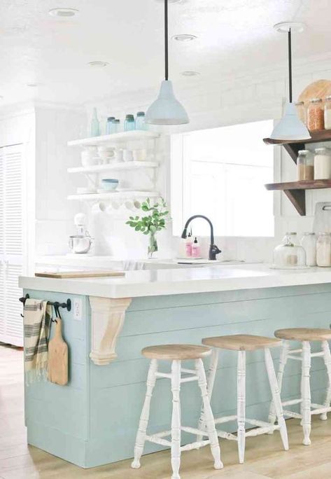 a dreamy coastal kitchen with white open shelving, an aqua kitchen island, matching pendant lamps and tableware, vintage stools and black fixtures Kitchen Beach House, Beach Home Interiors, Aqua Kitchen, Blue Kitchen Island, Light Blue Kitchens, Coastal Kitchen Decor, Teal Kitchen, Kitchen Design Color, Beach Kitchens