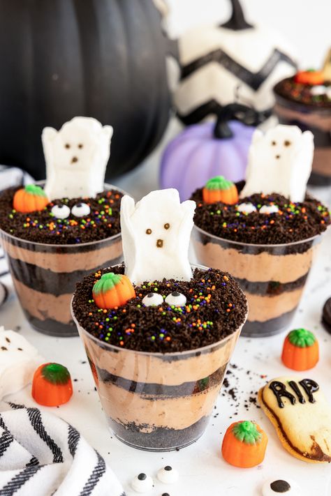 Looking for a spooky, fun, and easy treat to serve at your next Halloween party? These Graveyard Pudding Halloween Dirt Cups are perfect for kids and adults alike! Halloween Treats Dirt Cups, Halloween Pudding Dirt Cups, Dirt Cup Halloween, Halloween Cup Dessert, Halloween Graveyard Dirt Cups, Pudding Halloween Cups, Spooky Dirt Cups, How To Make Dirt Cups, Halloween Dirt Pudding Cups