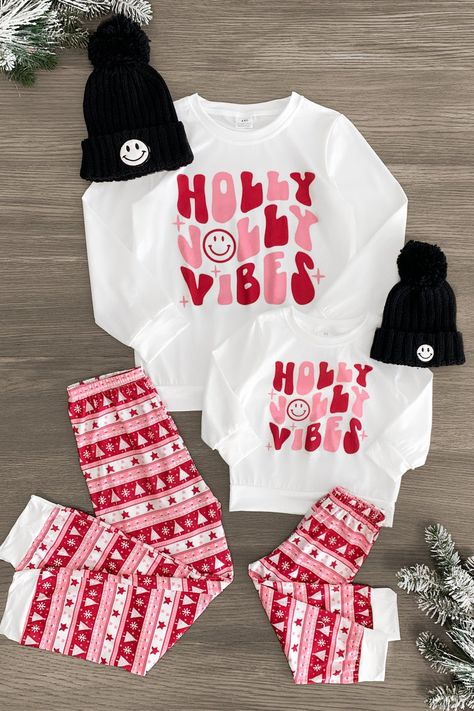 *Adult & child sets sold separately* Pajama set features a white long sleeve top and pair of Nordic print pants Mom & child sets both feature a "Holly Jolly Vibes" design Soft fabric provides cozy all-night comfort Perfect for bedtime or a Christmas movie marathon Gift you and your little ones' wardrobe a seasonally sweet vibe with these "Holly Jolly Vibes" Pajama Sets. These pajama sets come with a long sleeve top and pair of matching bottoms. Both pieces are made from a soft fabric blend for c Matching Sister Christmas Outfits, Cricut Christmas Pajamas Family, Gift Ideas For Moms Christmas, Mommy And Me Christmas Pajamas, Christmas Pajamas Outfit, Christmas Movie Marathon, Christmas Matching Pajamas, Fabric Outfits, Family Matching Christmas Pajamas