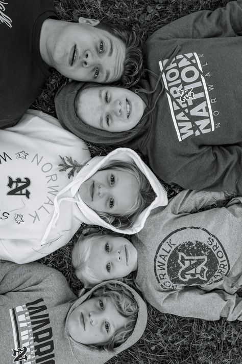 Des Moines and Norwalk, Iowa family photos - five siblings lay in the grass with their heads in a line pose for family photos wearing their sports sweatshirts with hoods. Children age from young school-aged to young adult. Teenage Sibling Photos, Goofy Sibling Pictures, Teen Sibling Portraits, Sibling Photoshoot Ideas Older Funny, Fun Sibling Photoshoot Ideas, 5 Sibling Photography, Teenage Sibling Photoshoot, 3 Siblings Photography Poses Older, Funny Sibling Photoshoot Ideas