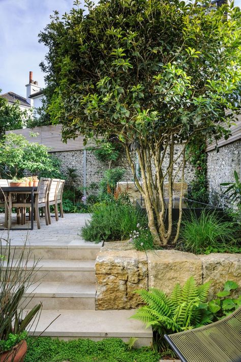 In this compact space, the garden has been paved using Purbeck stone in different forms to create a sense of harmony. The seating area is surrounded with tall planting including a multi-stem Osmanthus aquifolium. Its evergreen offers year round privacy. The pond and water spout add peace to the garden with the calming sound of water cancelling out the sound of the town traffic. Town Garden, Courtyard Gardens Design, Tiered Garden, Garden Privacy, Garden Designer, Small Garden Design, Courtyard Garden, Back Garden, Small Gardens