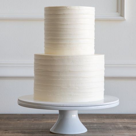 A simple buttercream cake with a dragged buttercream design, resembling the texture of tree bark. We suggest leaving your cake out at room temperature for at least 3 hours before serving to allow the buttercream to soften for optimal taste and texture. Ripple Wedding Cake, Three Tier White Wedding Cake, Wedding Cake For 150 Guests, Plain Wedding Cakes Simple, Basic White Wedding Cake, Small Wedding Cakes Two Tier, Wedding Cake Without Flowers, Simple Tiered Wedding Cake, Textured Buttercream Wedding Cake