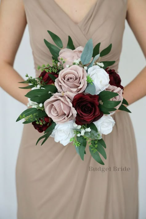 This lovely assortment of burgundy, mauve and white roses is bound to turn heads on your wedding day. This lovely cascading brides’ bouquet from the is an absolutely breathtaking arrangement for any bride to be, in any season. Bright greenery and babies breath complete the look and add a delicate realism to this beautiful bouquet. This bouquet is 10” wide, 18” long, and is crafted by our in-house florists without using a foam base to anchor the flowers to the bouquet. Instead, we wire our bouque Mauve Burgundy Green Wedding, Wedding Bouquets Bride Roses, Burgundy Wedding Bouquet, Small Bridesmaid Bouquets, Fake Wedding Flowers, Sage Eucalyptus, Small Bridal Bouquets, Fresh Wedding Flowers, Fake Wedding