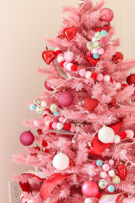 closeup of pink Christmas tree with red, white, and pink pom garland and red heart ornaments, pink glitter ornaments and white ornaments White Christmas Ornaments Aesthetic, Pink Peppermint Christmas Tree, Pink And Red Christmas Tree Decorations, Pink Red And White Christmas Decor, Red Pink Christmas Tree, Red And Pink Christmas Decor, Pink Red Christmas Tree, Red And Pink Christmas Tree, Pink Tree Decorations