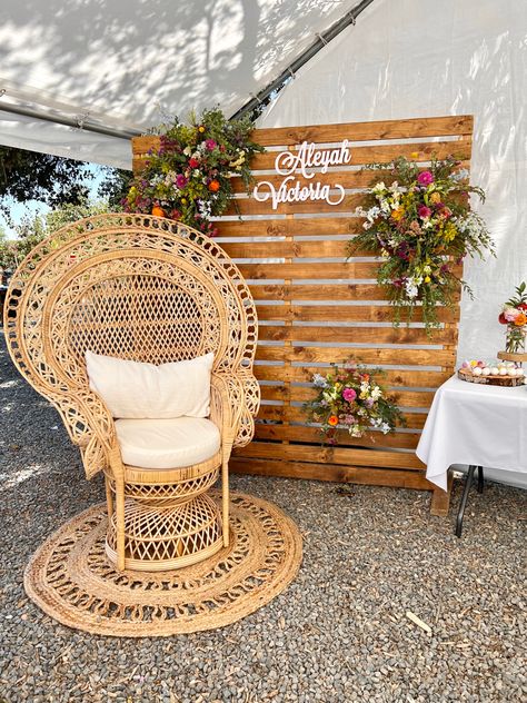 Wood backdrop with spring florals and a boho chair perfect for a baby shower. Wicker Party Decor, Peacock Chair Backdrop, Baby Shower Floral Backdrop, Easy Baby Shower Backdrop, Boho Floral Baby Shower Ideas, Baby Shower Mom Chair, Baby Shower Chair Ideas, Baby Shower Chair For Mom, Baby Shower Picture Backdrop