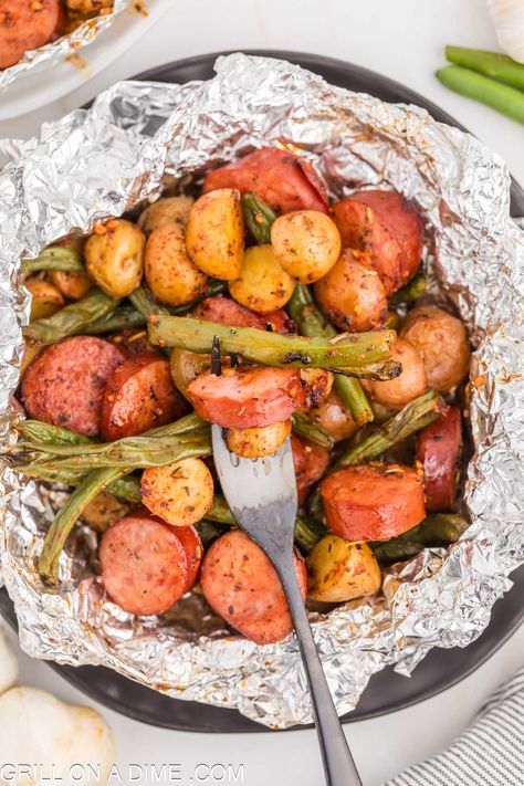 Sausage Foil Pack makes an easy weeknight meal. Load the foil pack with veggies, sausage and simple seasoning for a flavorful meal idea. I love the way the grill cooks this foil packet dinner. Because of how quick and easy it is and the smoky flavor. #eatingonadime #sausagefoilpack #foilpackdinner Quick Meals To Feed A Crowd, Easy Meals To Feed A Crowd, Grilling For A Crowd, Meals To Feed A Crowd, Potato Foil Packets, Easy Vacation Meals, Summer Suppers, Tin Foil Dinners, Summer Supper