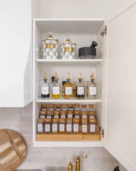 We just did a spice cabinet makeover and I love how it turned out. We bought a wood spice rack, spice jars with wood lids, gold bottle dispenser, and beautiful checked canisters. Click the link to find out where we bought them! Spice Jars With Wood Lids, Gold Spice Jars, Spices Organization Cabinet, Upper Spice Cabinet, Kitchen Spices Storage Ideas, Spice Jar Organization, Pawson House, Apartment Manifestation, Organized Aesthetic