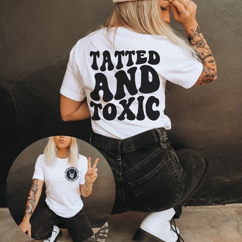 Get ready to rock your edgy style with our Tatted And Toxic t-shirt! Made from 100% cotton, this unisex shirt is perfect for any occasion. Its comfortable fit and unique design will make you stand out in a crowd. Show off your rebellious side with our Tatted And Toxic shirt. See the size chart below for measurements to ensure that you get the perfect fit Current processing time is 5-10 business days Tshirt Saying Ideas, Cute Shirt Prints, Cute Shirts To Make With Cricut, Cricut Graphic Tee Ideas, Edgy Tshirt Designs, Cricut Projects Clothes, Tattoo T Shirt Design Ideas, Vinyl T Shirt Designs, Diy Cricut Shirts