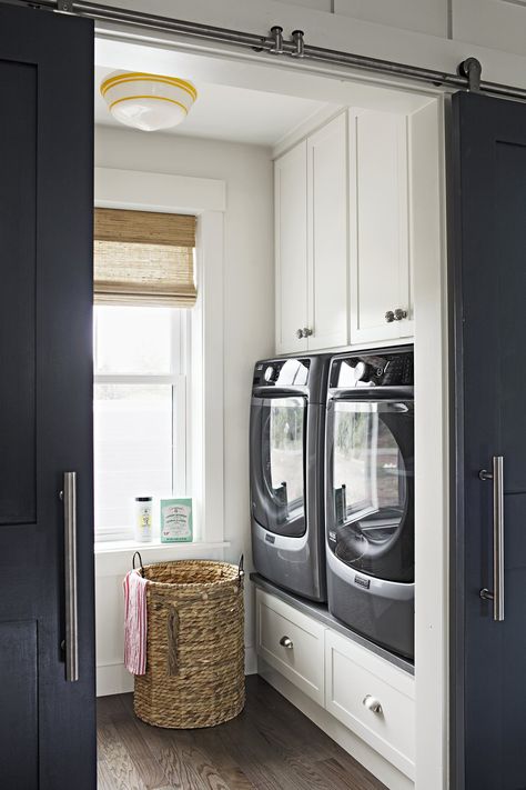 The compact laundry room is super-functional thanks to built-ins surrounding the washer and dryer, and another wall of cabinets with a countertop for folding clothes on the opposite side of the room. Redi-Prime Shaker-style 8782 barn doors; simpsondoor.com. Schoolhouse ceiling fixture by barnlightelectric.com. Wendy Bellissimo woven shade by smithnoble.com Compact Laundry Room, Laundry Room Organization Storage, Room Storage Diy, Mudroom Laundry Room, Farmhouse Laundry Room, Laundry Room Remodel, Laundry Room Inspiration, Small Laundry Rooms, Small Laundry Room