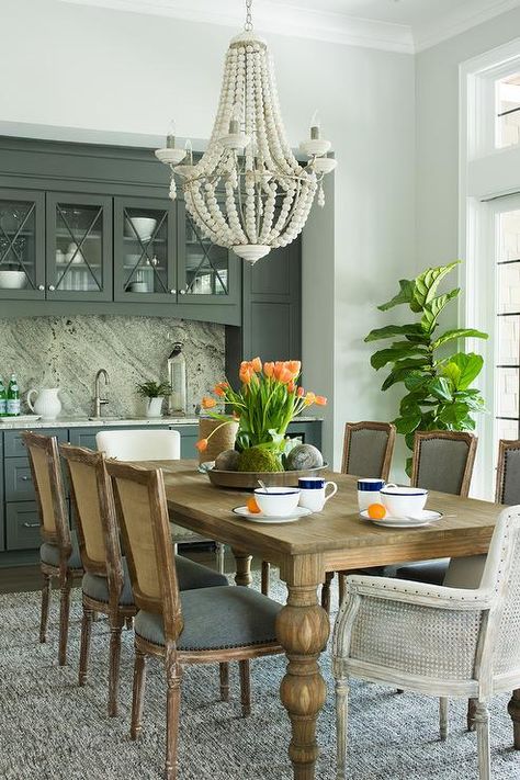 A white beaded French chandelier hangs above a wood dining table fitted with turned legs and surrounded by French cane back dining chairs accented with charcoal gray seat cushions. Cane Back Dining Chairs, Nantucket House, Dark Dining Room, Dining Table Makeover, Neutral Dining Room, French Country Dining Room, Dream Dining Room, Dining Room Cabinet, Revamp Furniture