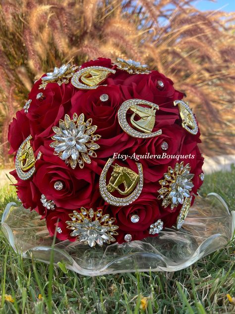 A beautiful vaquero themed bouquet for your special occasion. This bouquet is handmade to order with red silk roses, gorgeous sparkling gold brooches and rhinestones. We can do it in different colors. Please select the color of your choice. Please message me if you would like silver brooches instead.  *This bouquet is 10 inches in diameter* Please contact me with any questions! :) Red And Gold Roses Quinceanera Theme, Red Vaquero Quince, Quince Flowers Red, Quince Ramos Red, Quince Decorations Red And Gold Charro, Red Quince Theme Charro, Chambelanes Outfits Quinceanera Red, Quinceanera Ramos Red And Gold, Red And Gold Quinceanera Theme