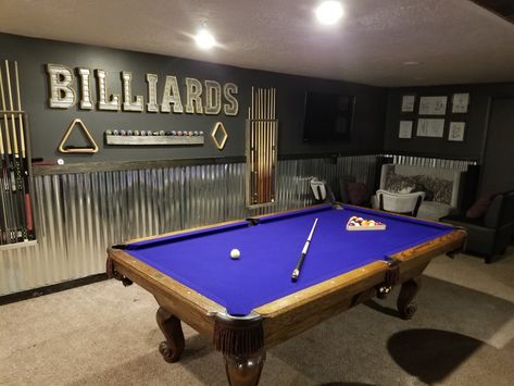 Basement billiards room with lounge areas and a wet bar. Pool table has a purple felt. Garage Billiard Room, Billiard Room Decor Ideas, Pool Table Entry Room, Basement Billiard Room, Pool Table Basement Bar Areas, Basement Game Room Decor, Basement Ideas With Pool Table, Basement Ideas Pool Table, Garage With Pool Table