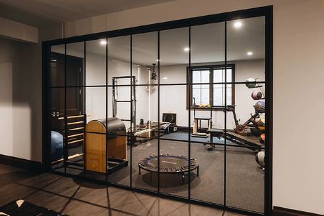 Home gym features black framed glass panels. Workout Bedroom, Basement Gameroom, Basement Workout Room, In Home Gym, Basement Gym Ideas, Fitness Rooms, Gym Basement, Chiro Office, Home Gym Basement