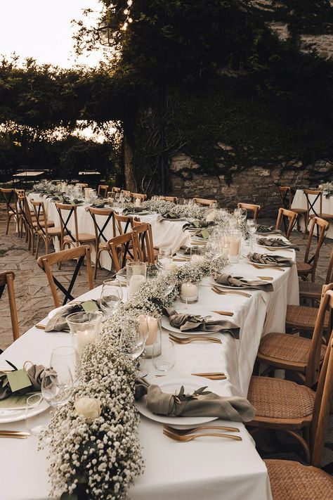 Winding reception tables covered in white tablecloths complete with babys breath table runner and fabric napkins Outdoor Table Decor Wedding, Wedding Table With White Tablecloth, White Tablecloth Decor, Wedding Table Set Up Long Tables, Wedding Table Covers Ideas Tablecloths, Outdoor Reception Table Decor, Wedding Table Gypsophila, Baby’s Breath Table Runner Wedding, Wedding Flower Arrangements Table Runner