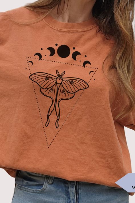 Introducing our Moth and Moon shirt, a unique and stylish way to show off your love for the celestial world. The shirt features a design of a moth and the phases of the moon, making it perfect for anyone who is fascinated by the celestial world. This shirt is made of soft, comfortable material, perfect for everyday wear. The shirt is suitable for casual or formal events, adding an earthy touch and a love of the natural world. Moth Shirt, Witchy Outfits, Spiritual Clothing, Spiritual Shirts, Phases Of The Moon, Moon Shirt, Boho Designs, Moon Phases, A Love