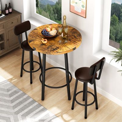 Create a beautiful interior relaxing space with this stylish and contemporary 3-piece pub table set. It will surely satisfy your demands for beauty and practicality. This small and compact dinette is the perfect setting for intimate dining in small spaces such as apartments, studios, or your home's kitchen. Chairs are ergonomically crafted with curved backrests to promote healthy posture. A great addition for all home and small dining spaces. Table Top Color: Vintage Brown | Millwood Pines Akill Small Round Dining Tables, Small Coffee Bar Ideas, Round Kitchen Table And Chairs, Bar Table And Chairs, Cozy Kitchen Nook, Pub Dining Set, Small Kitchen Table, Round Pub Table, Modern Bar Table