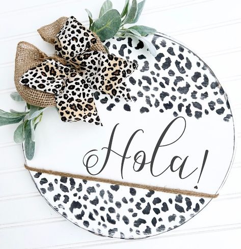 Hola Door Hanger | Hey There Door Hanger  Beautiful addition to your porch decor! Add a little farmhouse charm to welcome your guests. Loving the animal print on this round! Multiple colors & bow styles available to choose from. Choose between English or Spanish.  Our hand painted wood signs are stained throughout. Designs are painted on (no decals) and sealed. They come ready for hanging on your front door or entryway.  ~ Recommended for covered porch/or screened doors. Not to be on direct contact of rain or snow. Thank you for visiting our shop and supporting our small business! 🤍 Spanish Door Hanger, Bow Styles, Little Farmhouse, Wood Stain Colors, Dark Wood Stain, Hand Painted Wood Sign, Year Round Wreath, Round Wreath, Painted Wood Signs