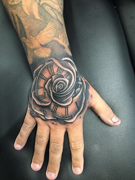 Rose hand tattoo by Greg at Holy Trinity Tattoos Clock Hand Tattoo, Dollar Rose, Rose Tattoo Hand, Revival Tattoo, Skull Hand Tattoo, Rose Hand Tattoo, Rose Tattoos For Men, Red Rose Tattoo, Tattoo Zeichnungen